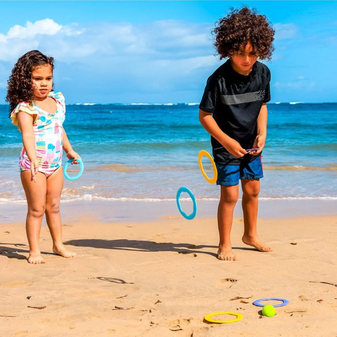 RiBi! Este versátil set de Bibio Toys invita a los peques a imaginar, moverse y crear sus propios retos, ya sea en la playa, la piscina, el parque o en casa.
¿Cómo se juega? Muy fácil: lanza la bola al centro de los aros en el suelo o sobre el agua y afina tu puntería. Luego, cambia el reto: coloca la bola y lanza los aros para encestar. ¡Y si lo prefieres, convierte los discos en barquitos flotantes o crea un circuito de obstáculos!