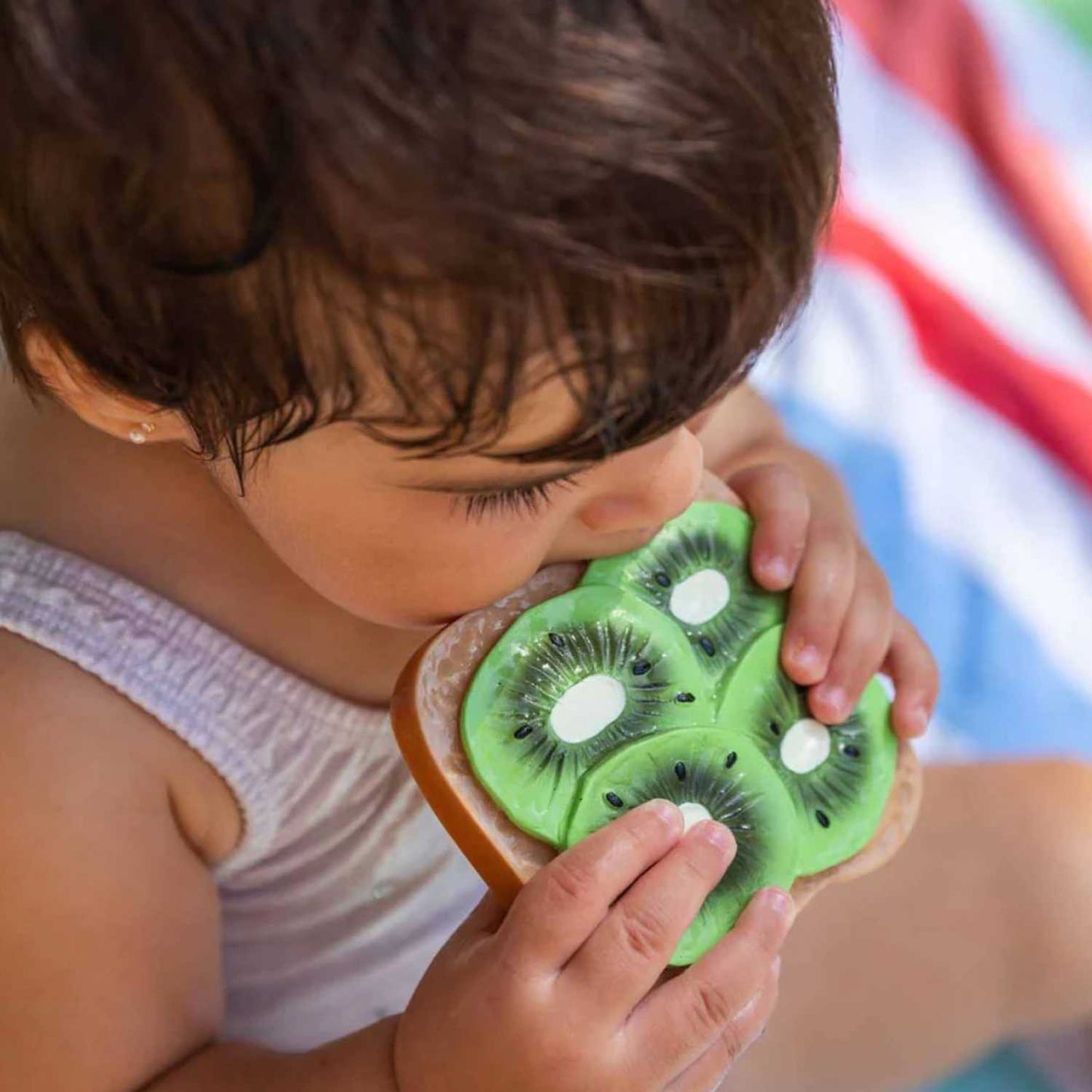 Mordedor en forma de Tostada con kiwi. Diseñado especialmente para las manos más pequeñas, es un accesorio ligero, blando y muy fácil de agarrar. Al no tener agujeros, se convierte en un juguete todoterreno súper seguro que tu bebé podrá usar también en la bañera, como elemento sensorial o para decorar su habitación. Encuentra los mordedores más divertidos y seguros en nuestra tienda online www.manodesantaoficial.es.