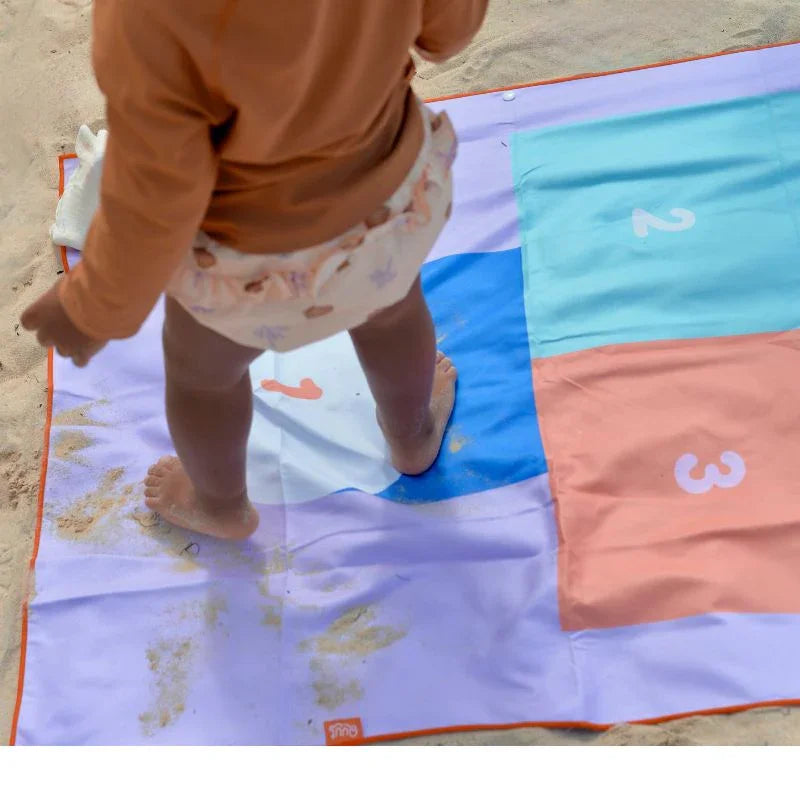 Conviértete en la mamá (o papá) más práctica del verano con esta toalla 2 en 1 que hará las delicias de peques y mayores. Por un lado, un clásico juego de rayuela para saltar, reír y moverse; por el otro, un diseño fresco y colorido que enamora a primera vista. Perfecta para llevar a la playa, piscina, al parque o incluso al jardín.
Fabricada en microfibra de secado rápido, esta toalla es ligera, no retiene olores y la arena no se le pega. ¡Ideal para escapadas con niños! Además, se seca hasta tres veces m