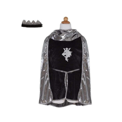 La túnica de terciopelo negro con capucha y mangas largas de tela de cota de malla está adornada con el emblema de un león de purpurina. La capa de punto líquido plateada, que se puede poner y quitar con velcro, completa el conjunto. Y no te olvides de la última pieza, la corona de caballero a juego con detalles plateadas&nbsp;