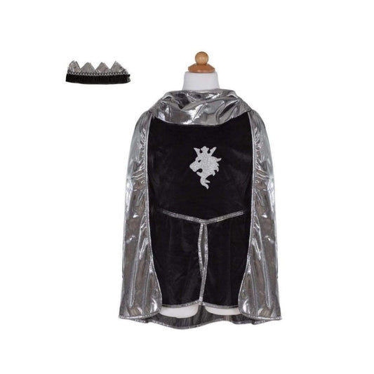 La túnica de terciopelo negro con capucha y mangas largas de tela de cota de malla está adornada con el emblema de un león de purpurina. La capa de punto líquido plateada, que se puede poner y quitar con velcro, completa el conjunto. Y no te olvides de la última pieza, la corona de caballero a juego con detalles plateadas&nbsp;