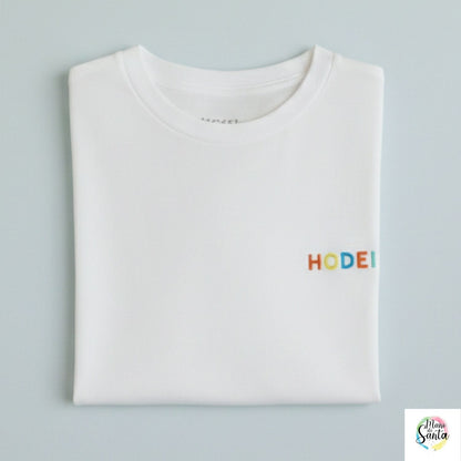 Compra la camiseta infantil personalizada con nombre bordado en relieve multicolor de Mano de Santa. Algodón premium 100% resistente y suave para niños.