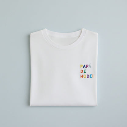 Camiseta Personalizada para Papá Blanca - "Papá de (Nombre)" - Bordado Multicolor Premium. Fabricada en tejido 100% algodón prelavado de alto gramaje (190g/m2). Corte contemporáneo moderno, construcción tubular y tacto ultrasuave. Incluye cuello de canalé fino y cinta tapacosturas trasera para mayor durabilidad. El regalo con más sentimiento para el Día del Padre, diseñado por Mano de Santa. Disponible en tallas de la XS a la 5XL.