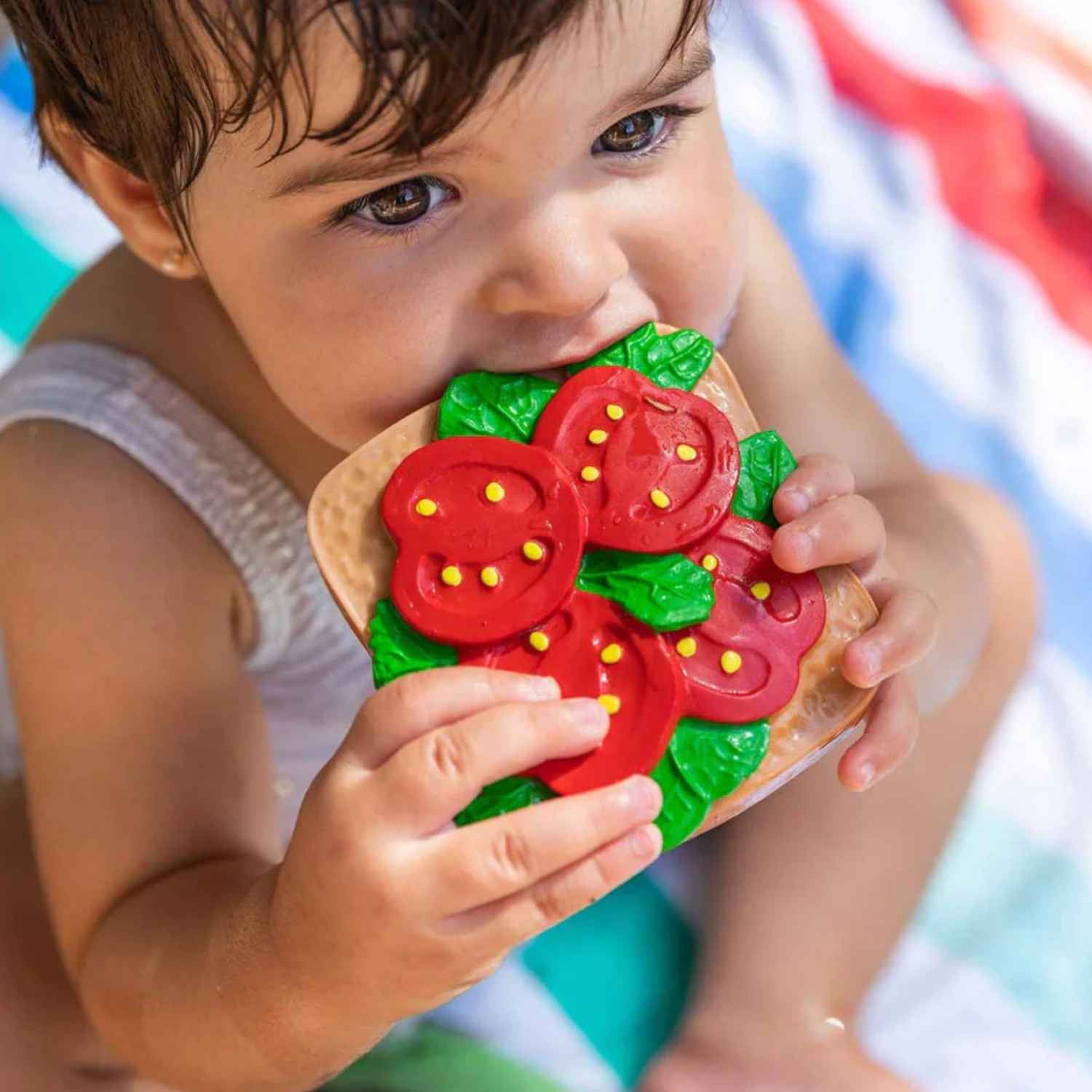 Mordedor en forma de Tostada con Tomate. Diseñado especialmente para las manos más pequeñas, es un accesorio ligero, blando y muy fácil de agarrar. Al no tener agujeros, se convierte en un juguete todoterreno súper seguro que tu bebé podrá usar también en la bañera, como elemento sensorial o para decorar su habitación. Encuentra los mordedores más divertidos y seguros en nuestra tienda online www.manodesantaoficial.es.