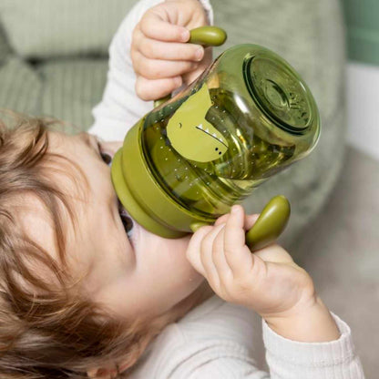Descubre el Vaso Anti-derrame 360 Dino de Trixie. Taza de aprendizaje con asas en Tritan™ resistente. Ideal para que los niños beban solos sin manchas ni fugas.