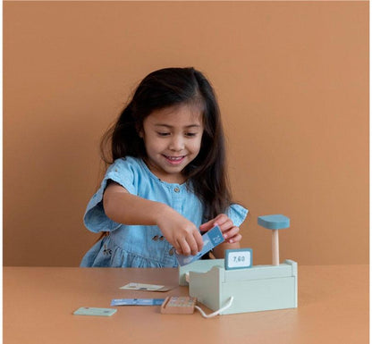 NIÑA MORENA JUGANDO CON CAJA REGISTRADORA LITTLE DTCH DE MADERA EN NUEVO COLOR MENTA CON BOTONES BILLETES Y MONEDAS EN COLORES DE INSPO NORDICA, INCLUYE LECTOR DE CÓDIGO DE BARRAS , DATAFONO, TARJETA, BILLETES Y MONEDAS