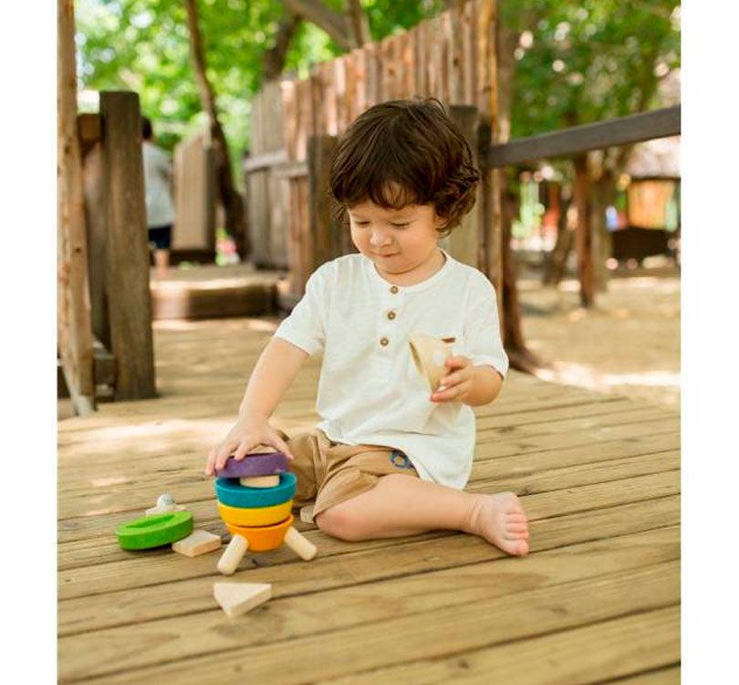 niño en el parque jugando con cohete apílable plantos multicolor de madera de la marca PLANTOYS