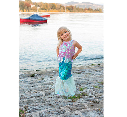 niña rubia en el puerto con Descubre un mundo submarino encantador con nuestro vestido de sirena. Este conjunto morado es perfecto para que tu hija se sienta como una princesa del mar. Combina lentejuelas, conchas marinas, estampado de escamas y una falda de tul estilo sirena para crear una aventura acuática llena de magia y estilo. ¡Sumérgete en la diversión con este vestido!