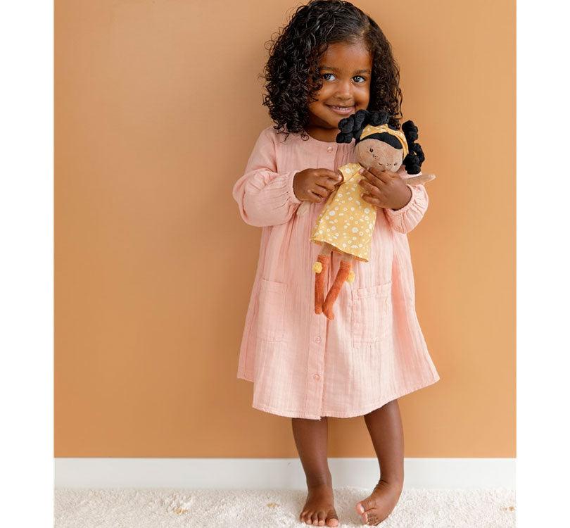 niña morena con pelo rizado jugando con muñeca blandita evi de Little Dutch de piel morena con cabello rizado negro vestido estampado mostaza y botas color teja 