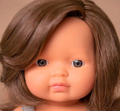 muñeca es una niña  caucásica con pelo liso castaño, con un adorable pelele gris topo primer plano Miniland