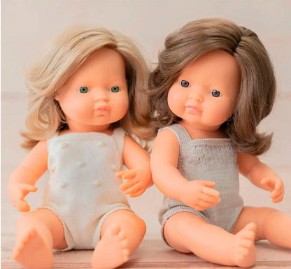 muñeca es una niña  caucásica con pelo liso castaño, con un adorable pelele gris topo Lifestyle