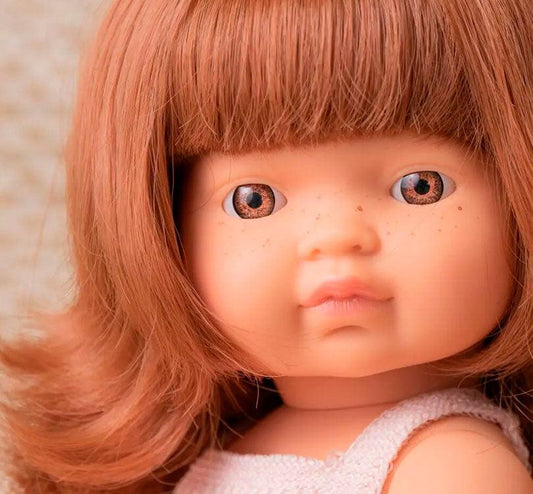 primer plano niña caucásica con pelo pelirrojo liso castaño , con un adorable pelele rosa claro marca miniland