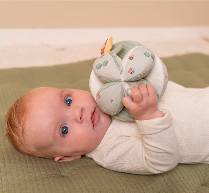 bebe tumbado con pelota Montessori con forma interesante es el desafío perfecto para tu pequeño.  Con diferentes texturas, patrones y lugares para agarrar, estimulará los sentidos y desarrollará el agarre. Además, su alegre sonido de cascabel interior mantendrá a tu bebé entretenido y emocionado.