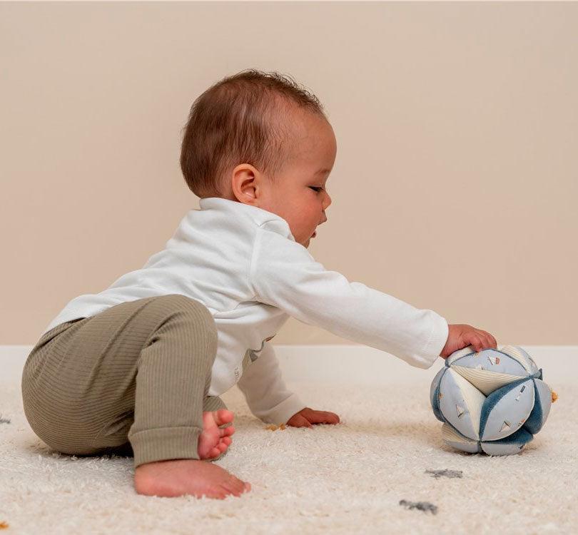 Niño sentado jugando con bola de agarre o pelota montessori de la colección sailors en colores adulones y crema de la marca Little Dutch