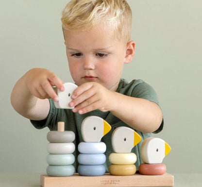 niño rubio jugando detrás del encajable para tratabajr primeros conteos, 4 filas para ensartar  aros de diferentes colores y tamaños, ordenados de mayor a menor por colores representando una familia de ocas de la marca Little Dutch