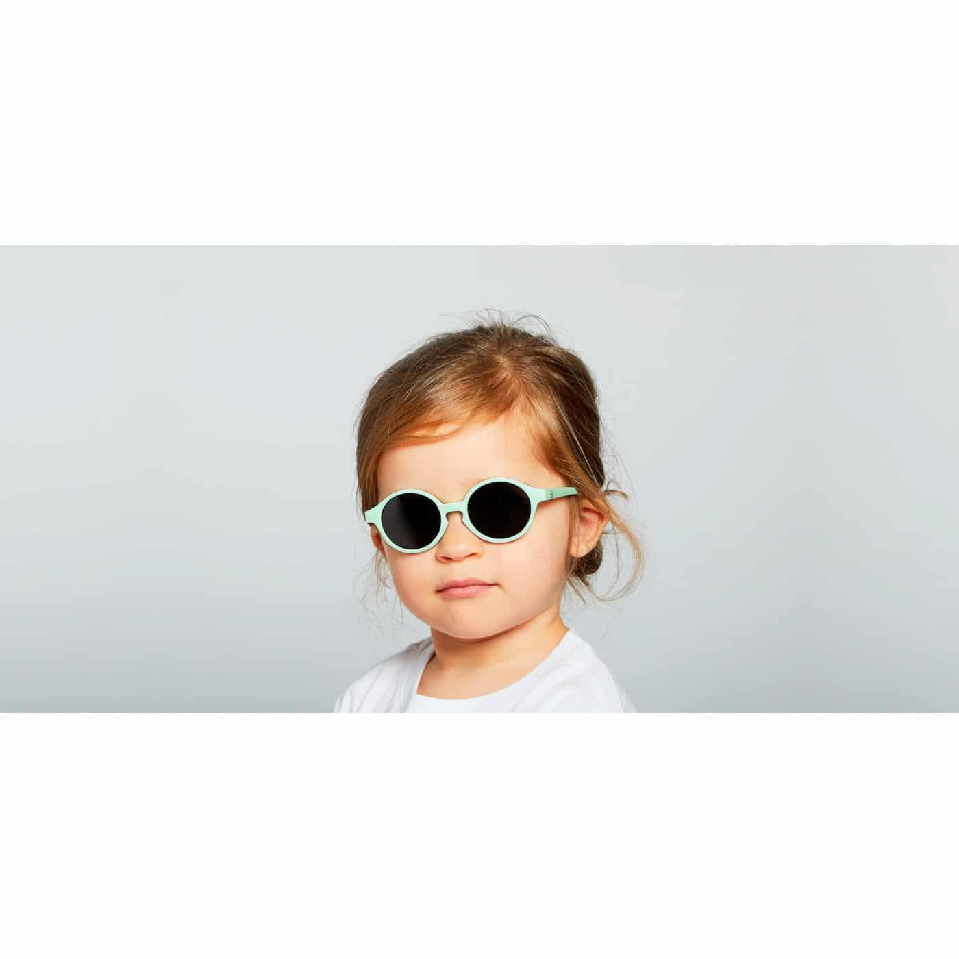 foto de life style con niña llevando Gafas de sol infantiles marca izipizi en talla 9-36 meses a, montura modelo d , redondeadas en color menta